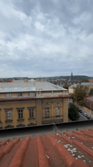 Prague rooftop panorama under cloudy skies, attic renovation inside
