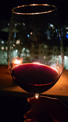 Person enjoys red wine by candlelight
