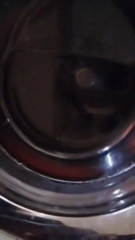 The camera peers into the dark, empty, and shiny interior of what appears to be a cylindrical metal container. Light reflects on the surface of the material, suggesting a polished or reflective finish. A small, circular indentation is visible at the center of the bottom surface of the container.