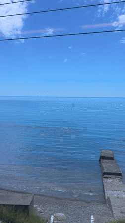 Train passenger films calm waters and concrete pier in Sochi