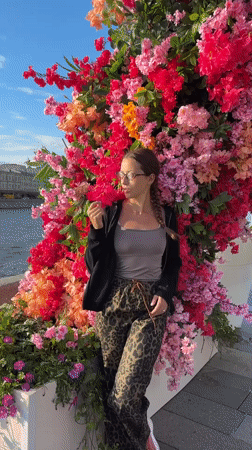 Moscow waterfront sees casual afternoon activity, woman poses among flowers