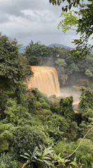 Sediment-heavy waterfall cuts through lush Vietnamese highland forest