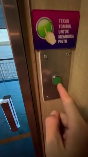 Ferry passenger operates door button near Ketapang, Indonesia