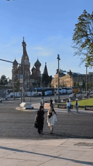 Two women walk across Moscow street on sunny afternoon