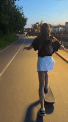 Woman skateboarding along Yenisei River embankment in Krasnoyarsk at dusk