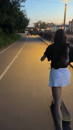 Woman skateboarding along Yenisei River embankment in Krasnoyarsk at dusk