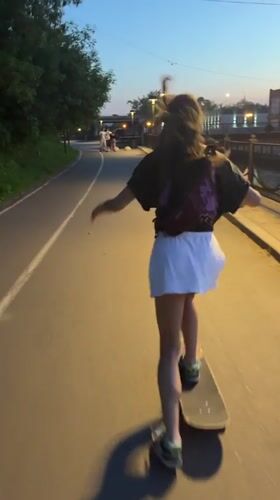 Woman skateboarding along Yenisei River embankment in Krasnoyarsk at dusk