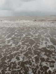 Overcast beach scene on Indonesia's coast, waves and murky surf