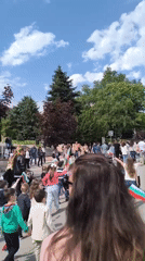 Crowd with children gathers outdoors on sunny day