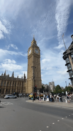Tourists photograph Big Ben and Parliament under cloudy London skies