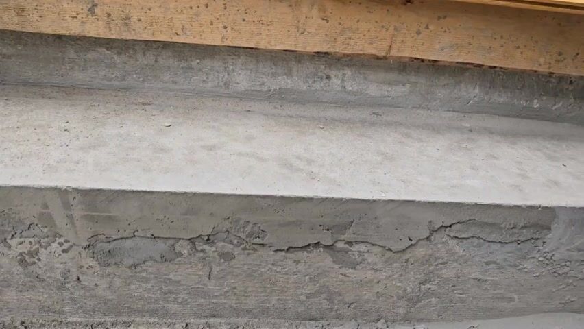 The video shows a close-up of a concrete structure, possibly stairs or a foundation, with visible cracks and surface imperfections. The concrete appears to be somewhat weathered or damaged. A tool is briefly visible in the frame, suggesting repair or modification work. A noise, likely from the tool, can be heard during the video. The environment seems to be an outdoor construction site.