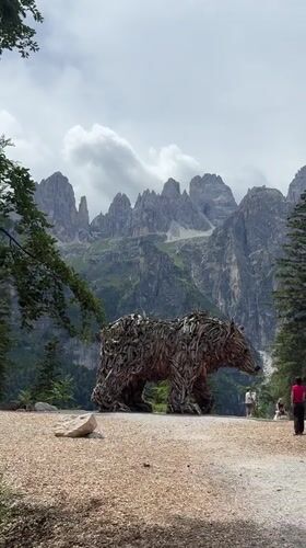 Driftwood bear sculpture against the Dolomites in Molveno