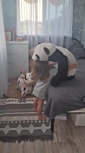 Toddler plays with stuffed panda in Russian bedroom