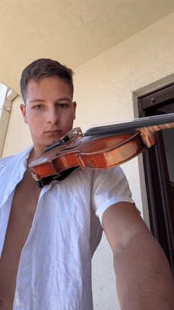 Violinist practices on Budva balcony with city ocean view