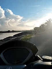 Motorcycle rider documents waterfront community life during morning journey