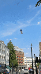 Blimp drifts over a busy London street on a summer afternoon