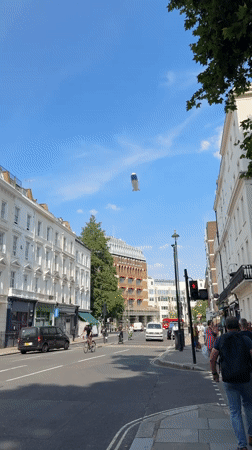 Blimp drifts over a busy London street on a summer afternoon