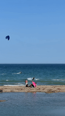 Kitesurfers work a choppy Estepona beach on a clear afternoon