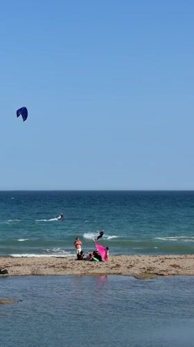 Kitesurfers work a choppy Estepona beach on a clear afternoon