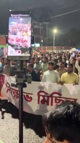 Nighttime procession with Bengali banners moves through Dhaka streets