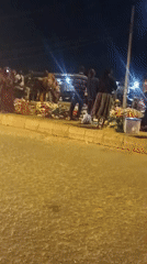 Nighttime street market operates in Bukuru, Nigeria with cattle truck