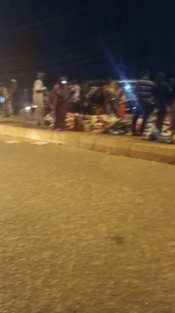 Nighttime street market operates in Bukuru, Nigeria with cattle truck