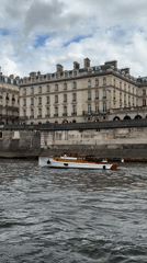 Passenger boat travels Seine River past Parisian stone embankment