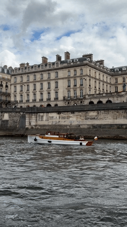 Passenger boat travels Seine River past Parisian stone embankment