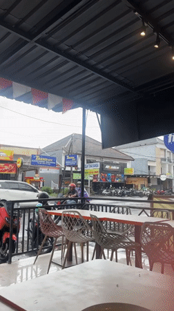 Rain shower hits outdoor cafe in Denpasar, Indonesia