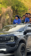 Blue-shirted group rides pickup truck through Ko Samui roads