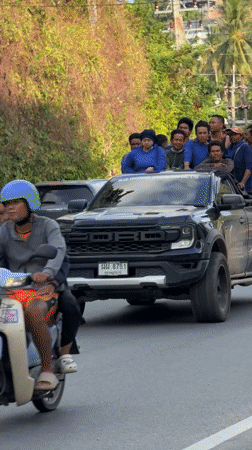 Blue-shirted group rides pickup truck through Ko Samui roads