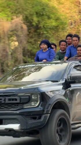 Blue-shirted group rides pickup truck through Ko Samui roads