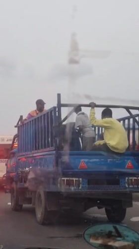 Blue cage truck moves through Lagos traffic during overcast day