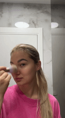 Woman applies makeup in bathroom during morning routine in Budva