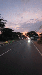 Dusk traffic on a wet Indonesian road, twilight sky overhead