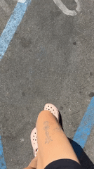 Person in pink Crocs stands on marked pavement in Malibu