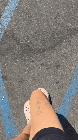 Person in pink Crocs stands on marked pavement in Malibu