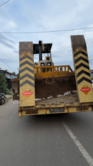 Heavy machinery transported through Indonesian villages on flatbed trailer