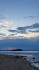 Three people watch sunset at Vekoshinka beach in Russia