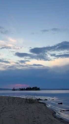 Three people watch sunset at Vekoshinka beach in Russia
