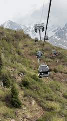 Colorful gondolas carry passengers up green mountainside near Almaty