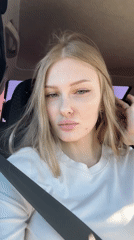 Woman sits in car, adjusts hair in Perm