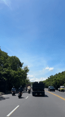 Sunny morning traffic observed on tree-lined Kuta road