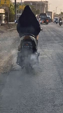 Scooter produces heavy white smoke on Indonesian road