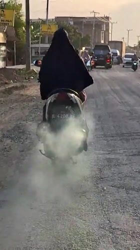 Scooter produces heavy white smoke on Indonesian road