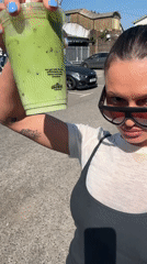 Woman documents sunny afternoon outing with green drink in Waverley
