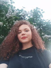 Woman in "AFFECTION" shirt photographed among spring blossoms, urban setting