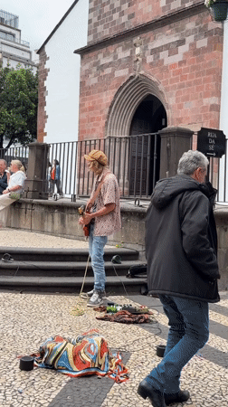 Street musician performs guitar in Funchal pedestrian square