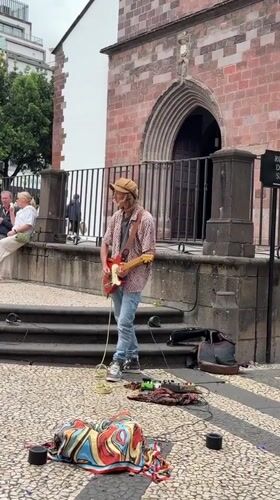 Street musician performs guitar in Funchal pedestrian square