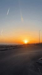 Person watches sunset from rocky overlook during golden hour